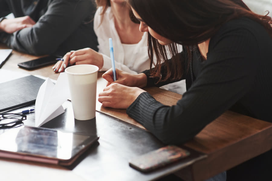 People working on laptops and a tablet around a table with coffee