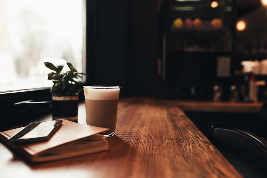 A cup of coffee, a notebook and a phone on a cafe table
