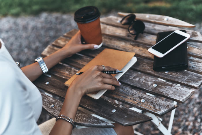 Making notes in a planner at a wooden outdoor table