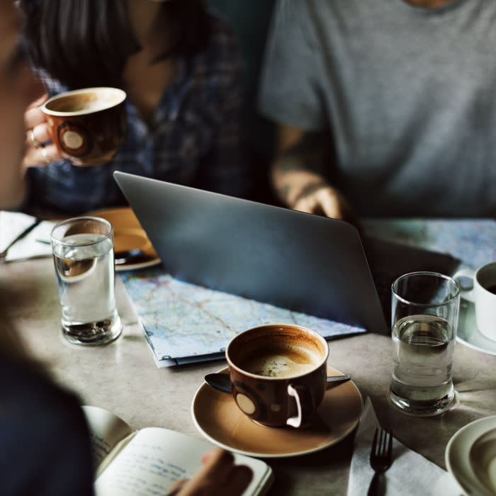 Friends with laptops and coffee cups around a cafe table